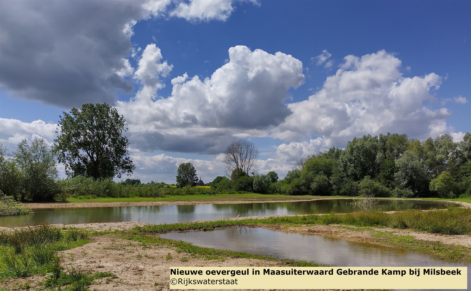 De nieuwe oevergeul in Maasuiterwaard Gebrande Kamp bij Milsbeek met wolken en een blauwe lucht erboven. 